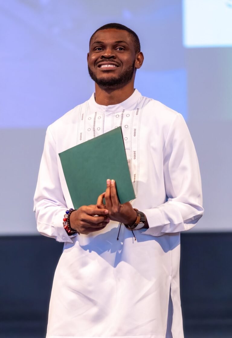 Daniel Appiah Gyekye holding a green folder on stage